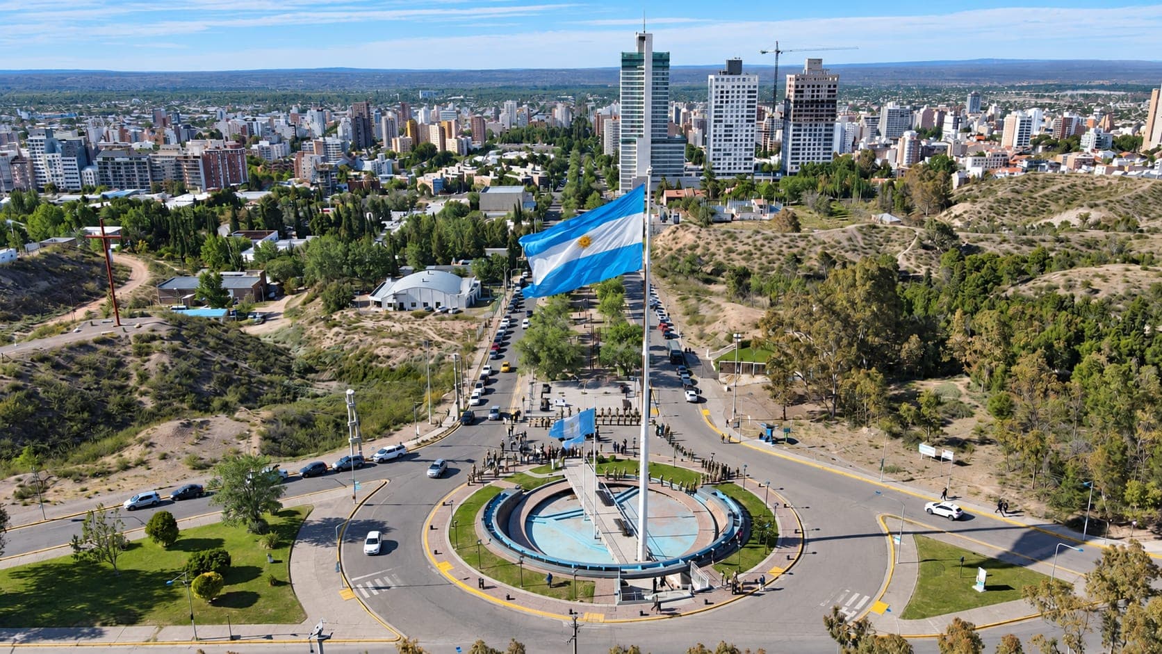 Vista aérea de Neuquén capital desde la barda, con la bandera argentina y los edificios del centro